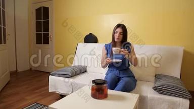 一个穿着蓝色西装的年轻女孩坐在沙发上，喝着茶想着什么。 <strong>茶饮</strong>